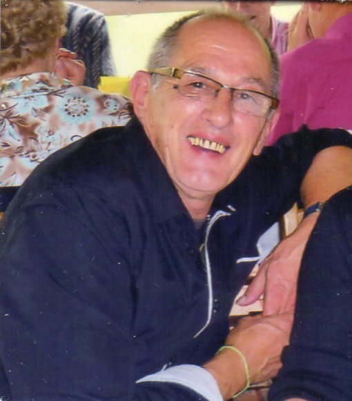 Jean-Louis Aparicio, souriant, en chemise sombre, assis à une table au milieu d’autres convives.